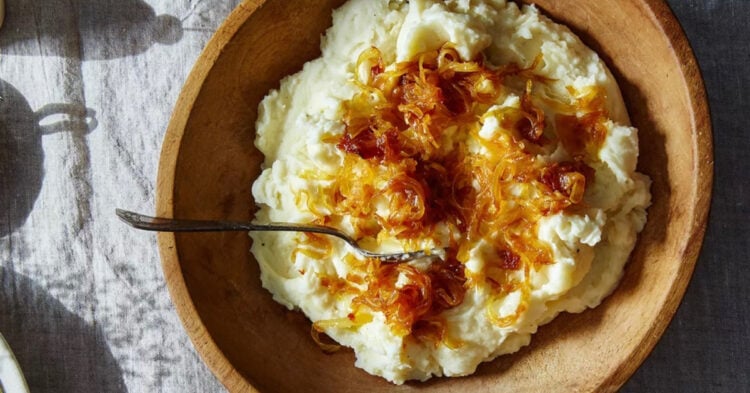 Mashed potatoes with caramelized onions and goat cheese in a wooden bowl.