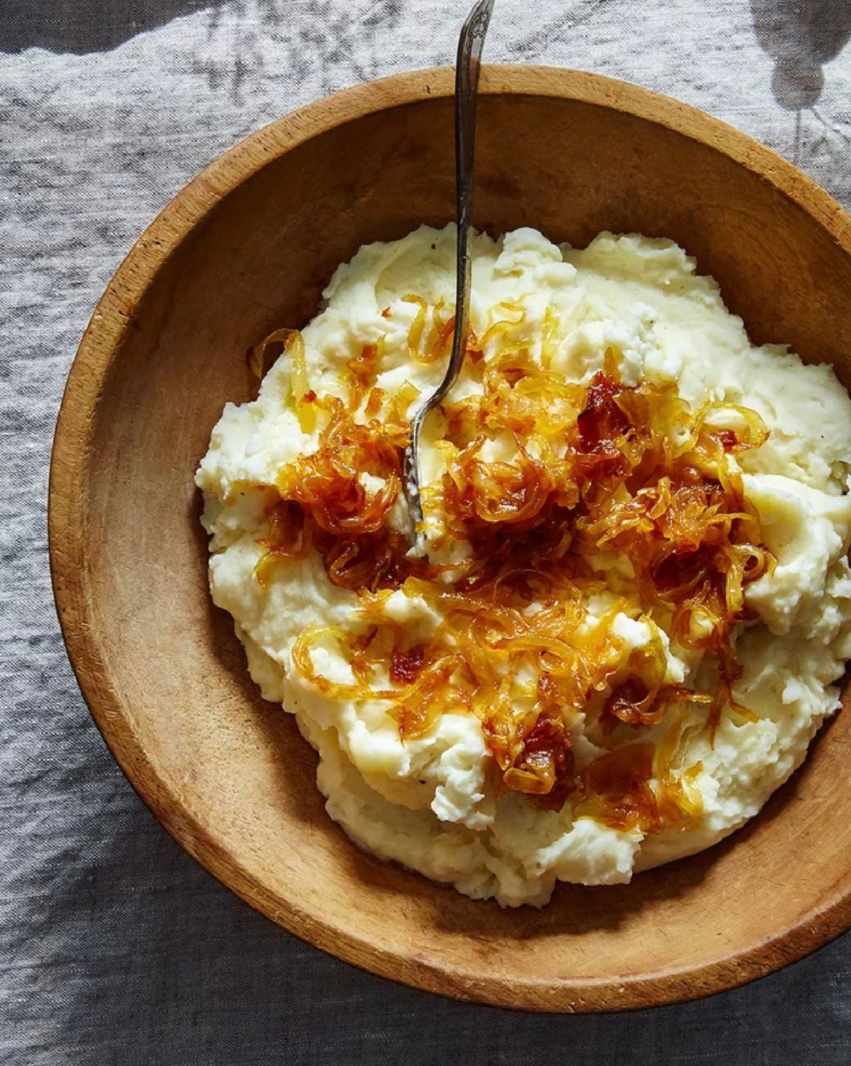 Mashed potatoes with caramelized onions and goat cheese in a wooden bowl.
