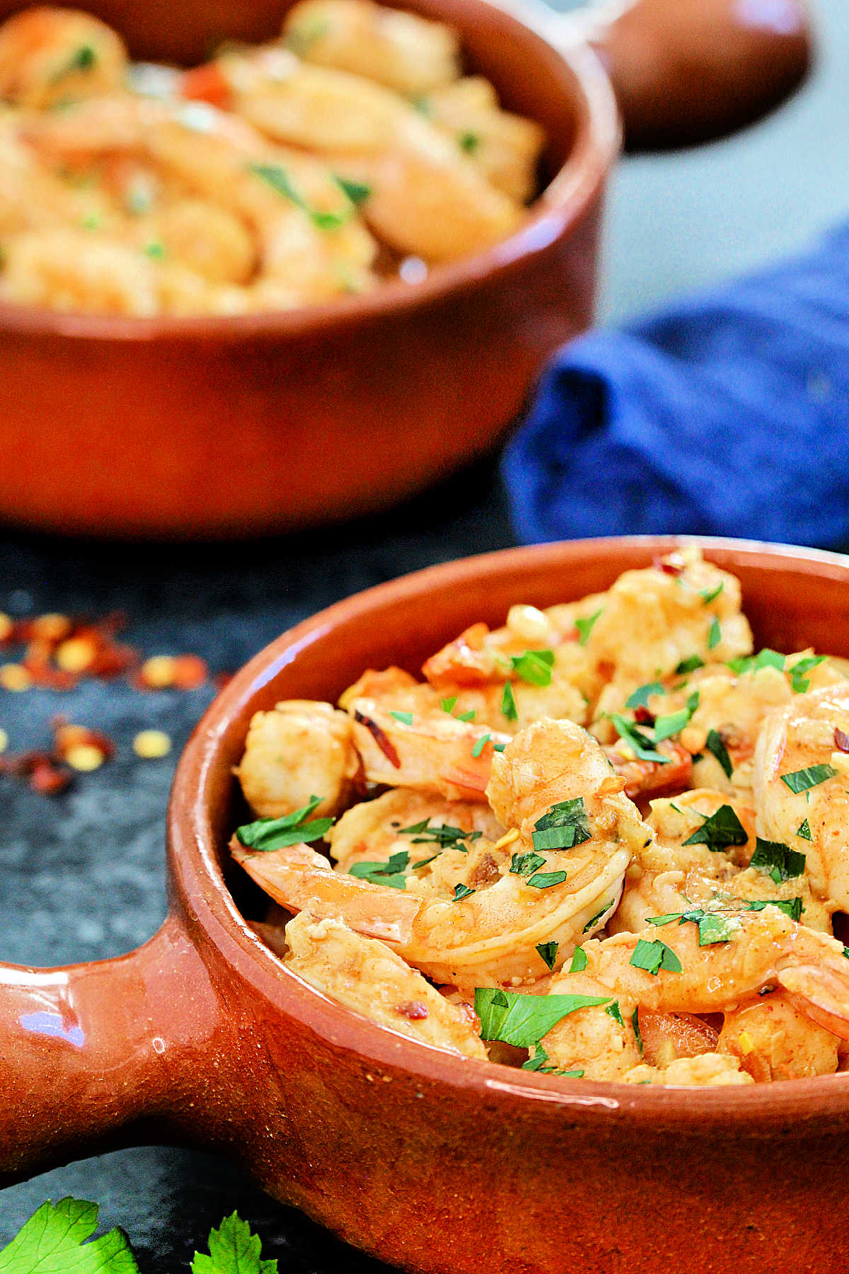 Close up shot of Spanish garlic shrimp in a brown dish.