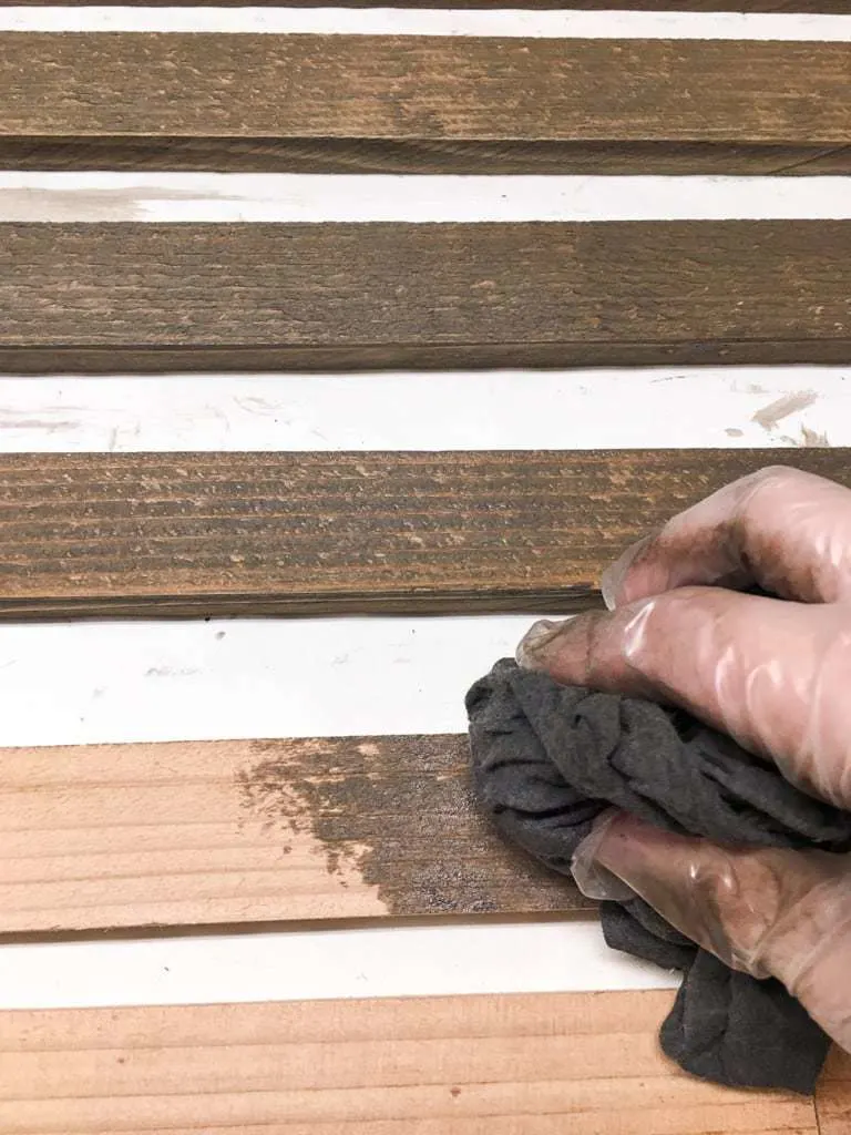 hand applying stain to boards for clematis trellis