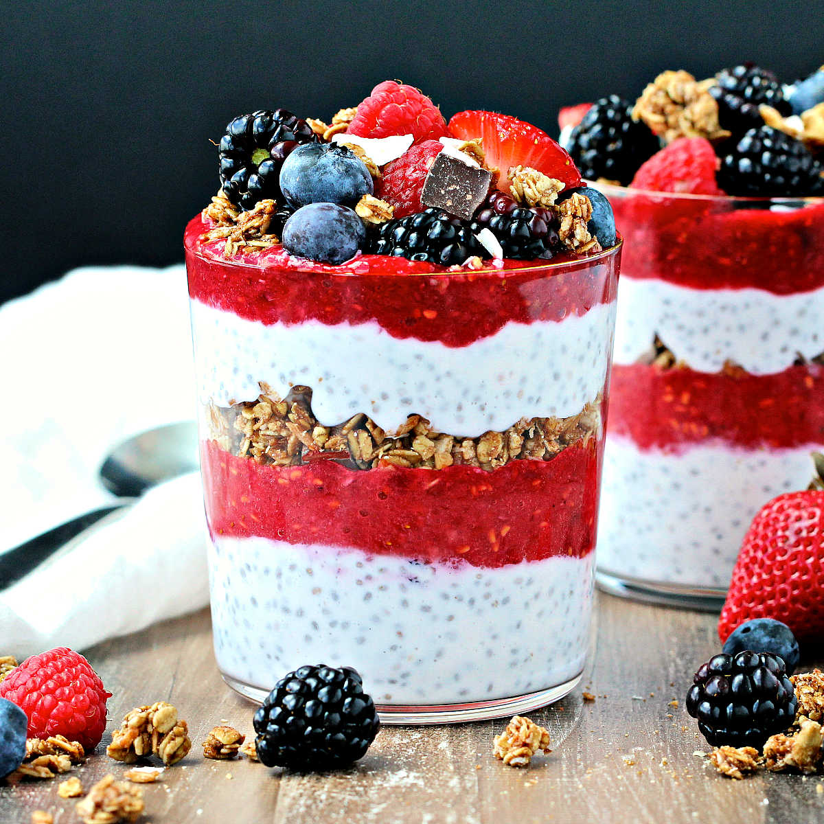 2 Berry Chia Pudding Parfaits on a wooden board.