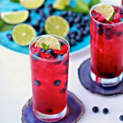 2 glasses of blueberry mint limeade garnished with fresh blueberries and lime slices.
