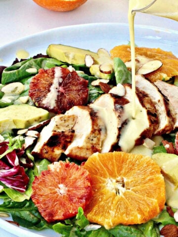Creamy citrus salad dressing being poured onto salad on a white plate.