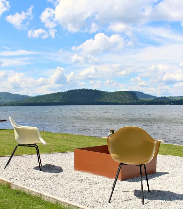 metal fire pit on pea gravel patio by lake