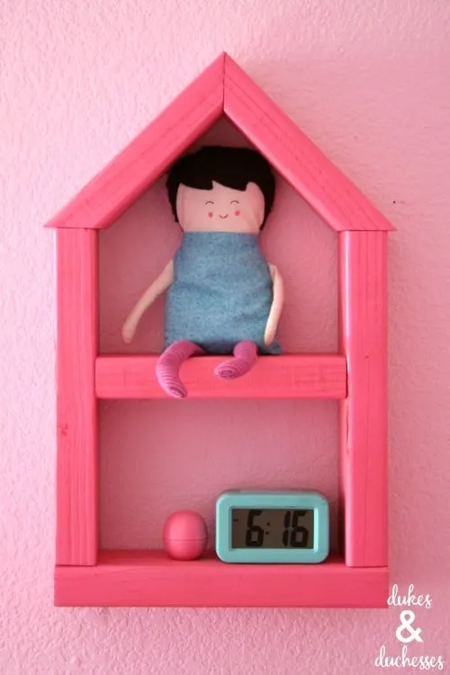 pink shelf shaped like a house made from one board