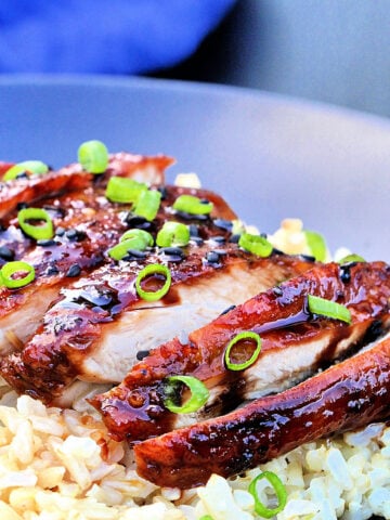 Sliced chicken teriyaki on a bed of brown rice.