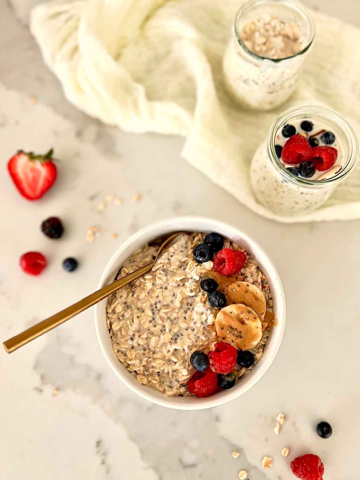 Overhead picture of healthy overnight oats in a bowl with two jars of overnights oats nearby.