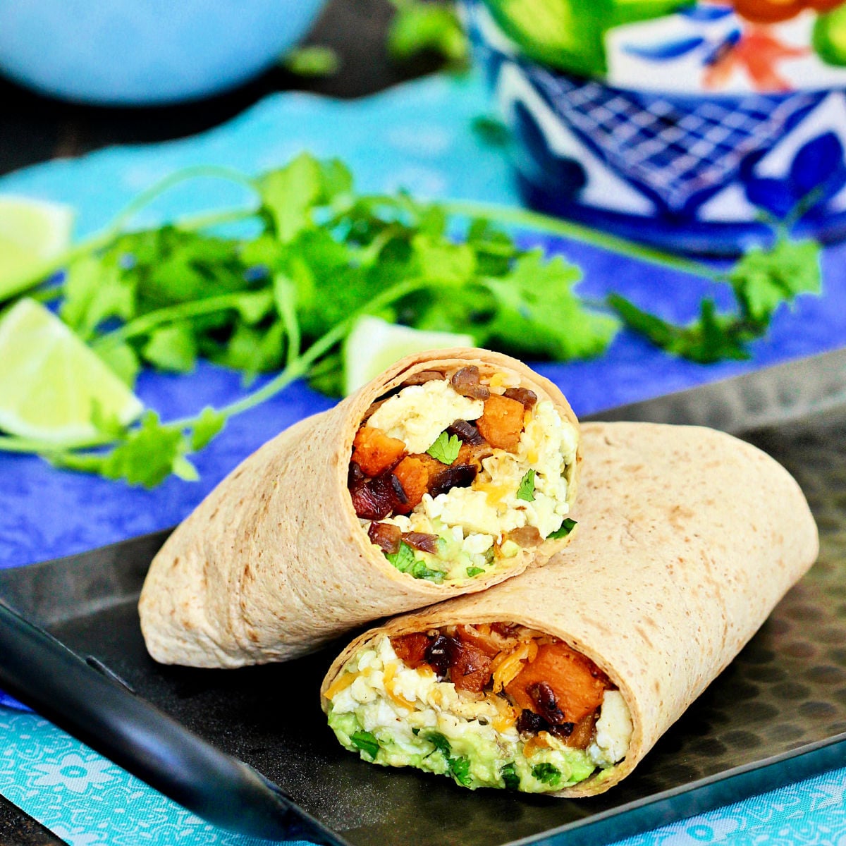 breakfast burrito cut in half on a plate.