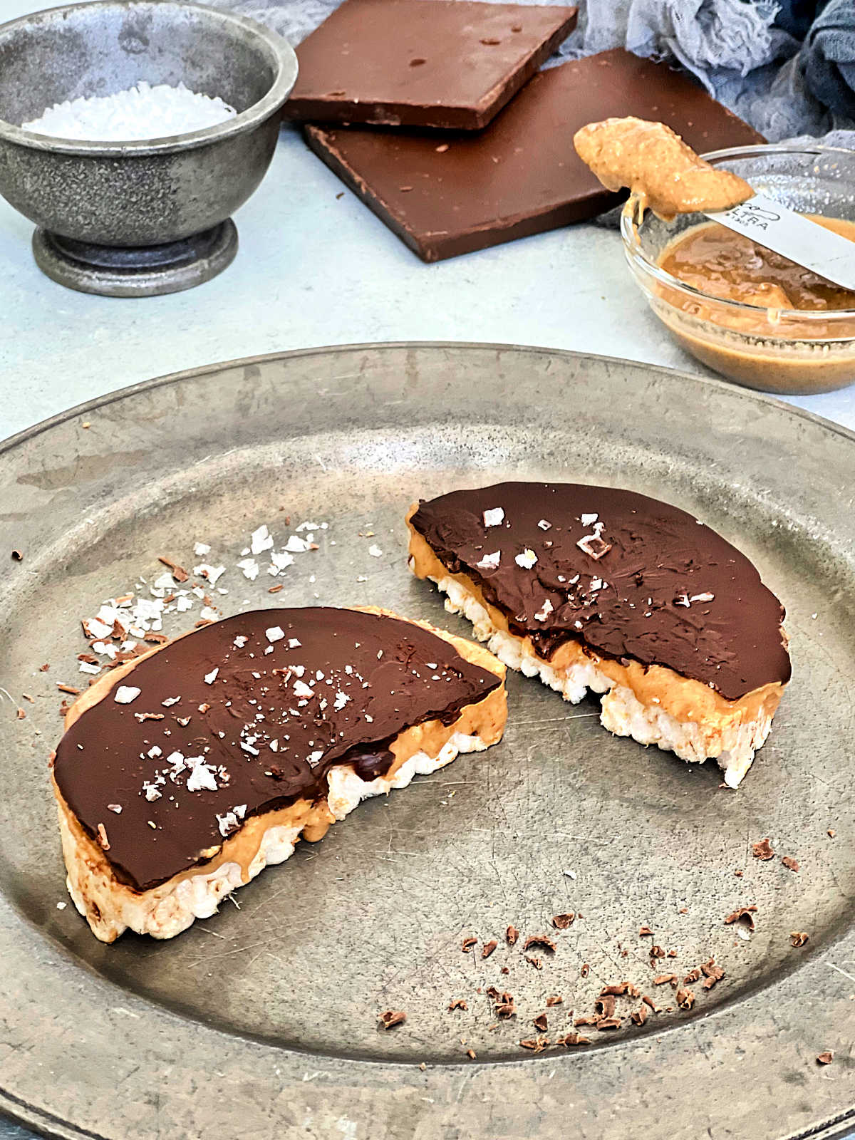 Giant peanut butter cup rice cake broken in half on a silver plate.