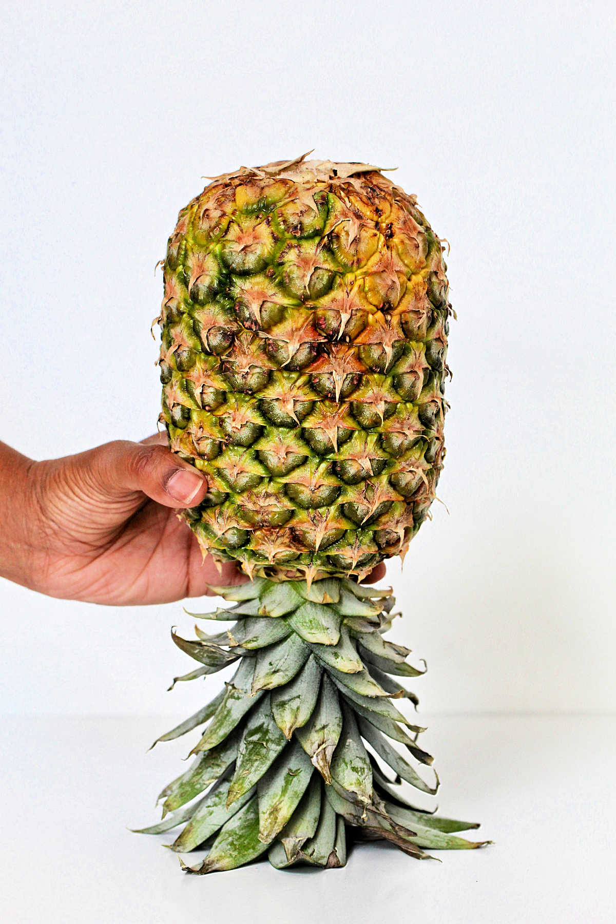 Holding a pineapple upside down.