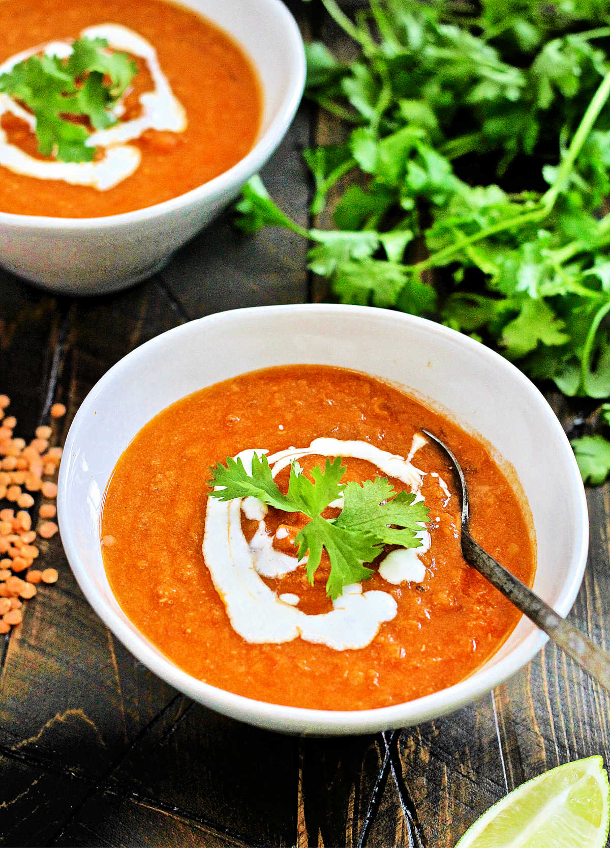 Coconut curry lentil soup in a white bowl with s spoon in it.