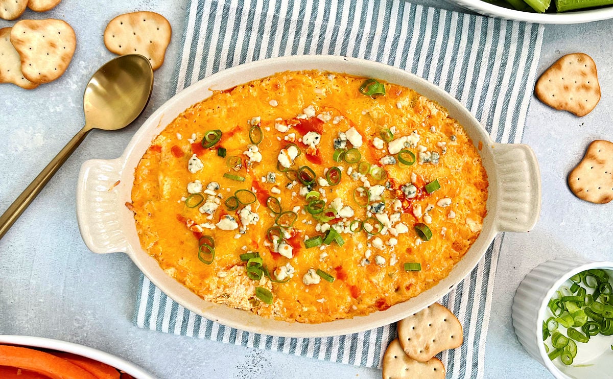 Buffalo chicken dip in an oval dish on a striped napkin.