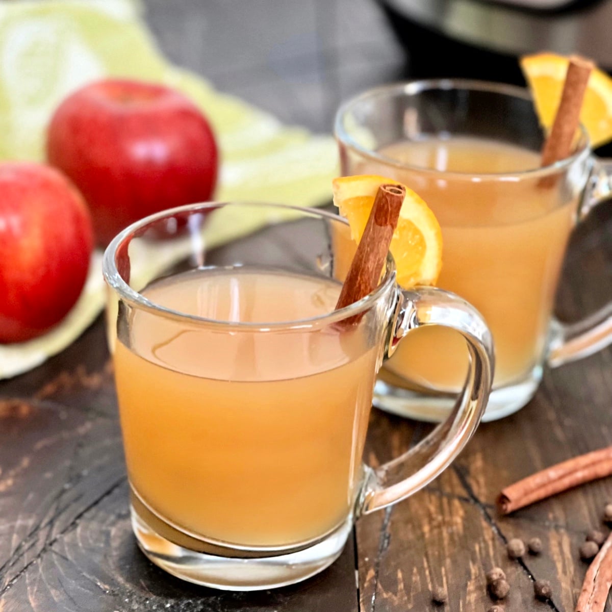 A glass of crock pot mulled cider with a cinnamon stick.
