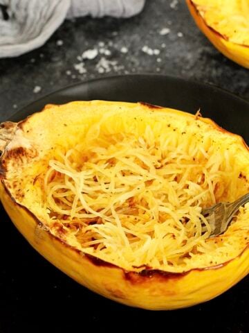 A spaghetti squash boat on a black plate.