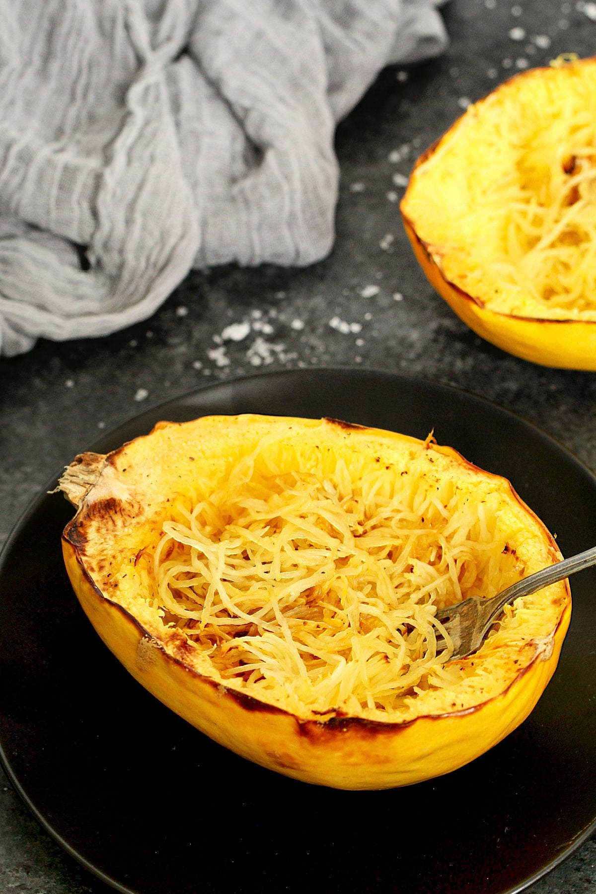 A spaghetti squash boat on a black plate.