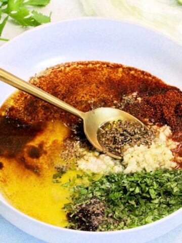 Mexican chicken marinade in white bowl with gold spoon.