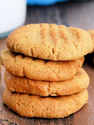 Stack of air fryer peanut butter cookies near a glass of milk and blue napkin.