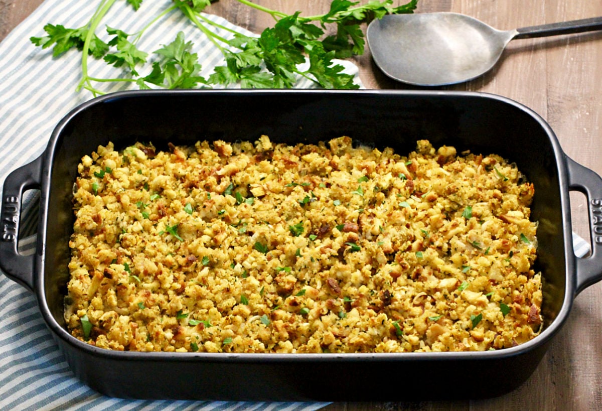 Turkey and Stuffing Casserole in a black baking dish with parsley nearby.