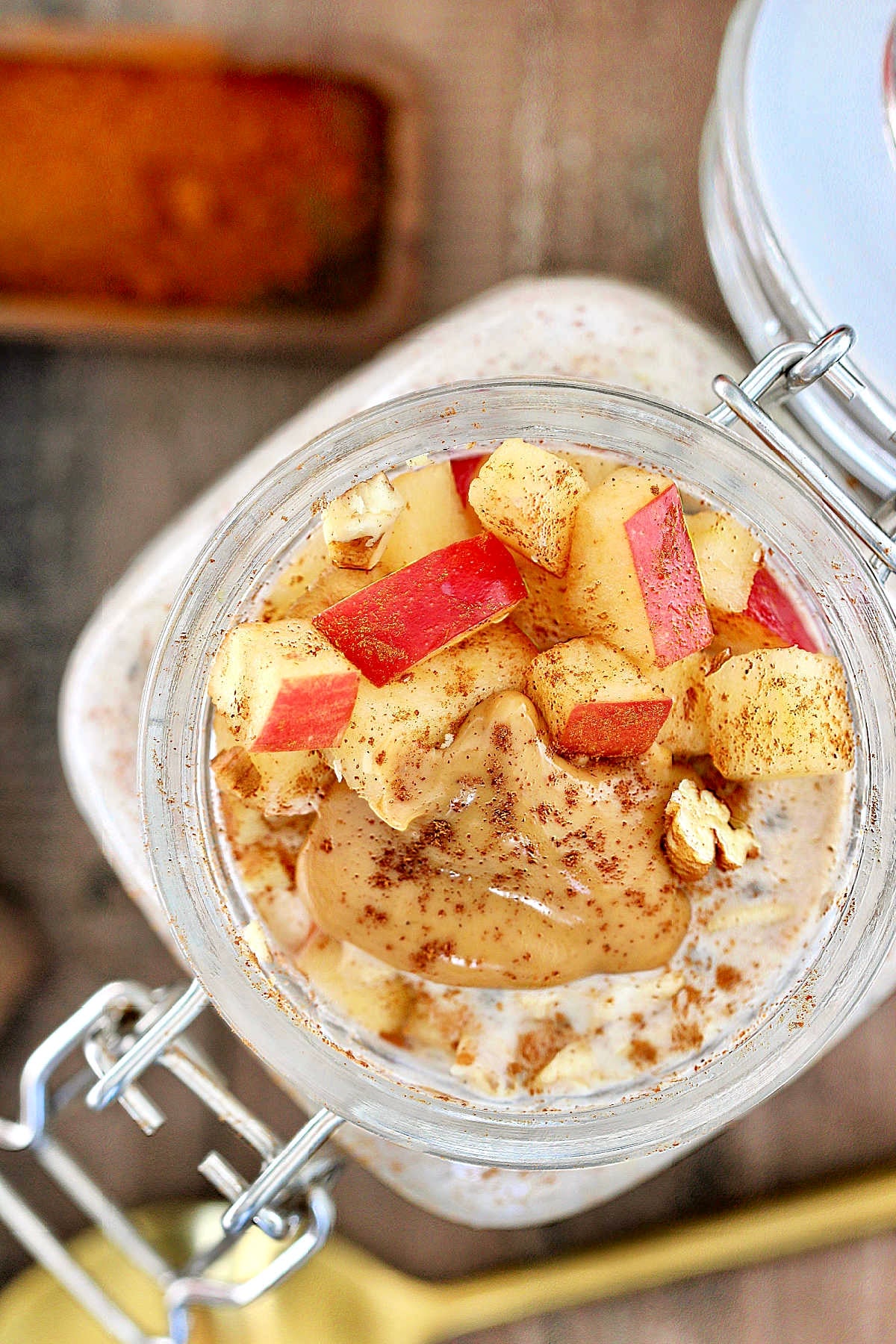 A overhead view into a jar of apple cinnamon overnight oats topped with chunks of apple and peanut butter.