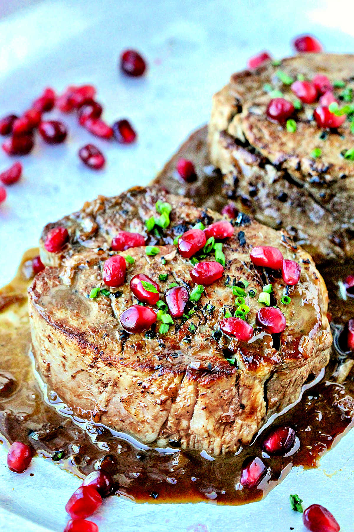 Two filet mignons with pomegranate sauce on a silver platter.