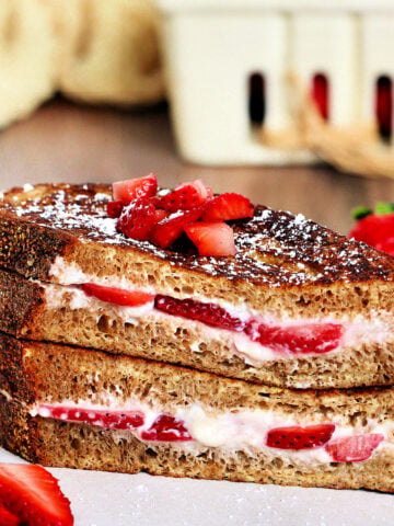 Two pieces of strawberry stuffed French toast stacked on a white plate.