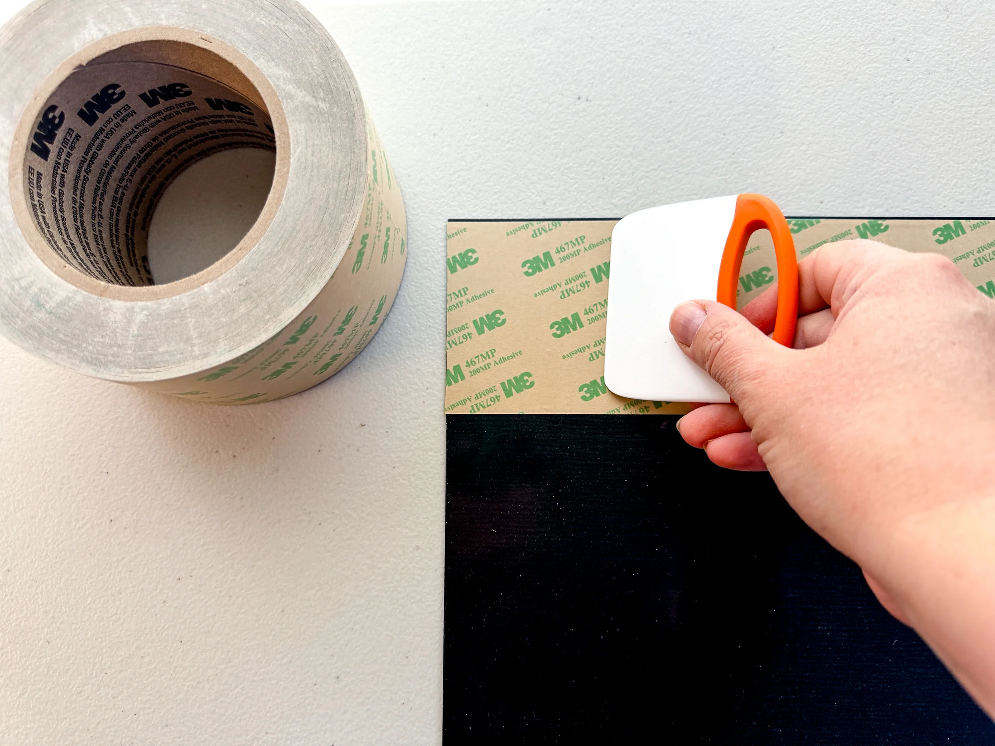 applying 3M adhesive to the back of the black acrylic