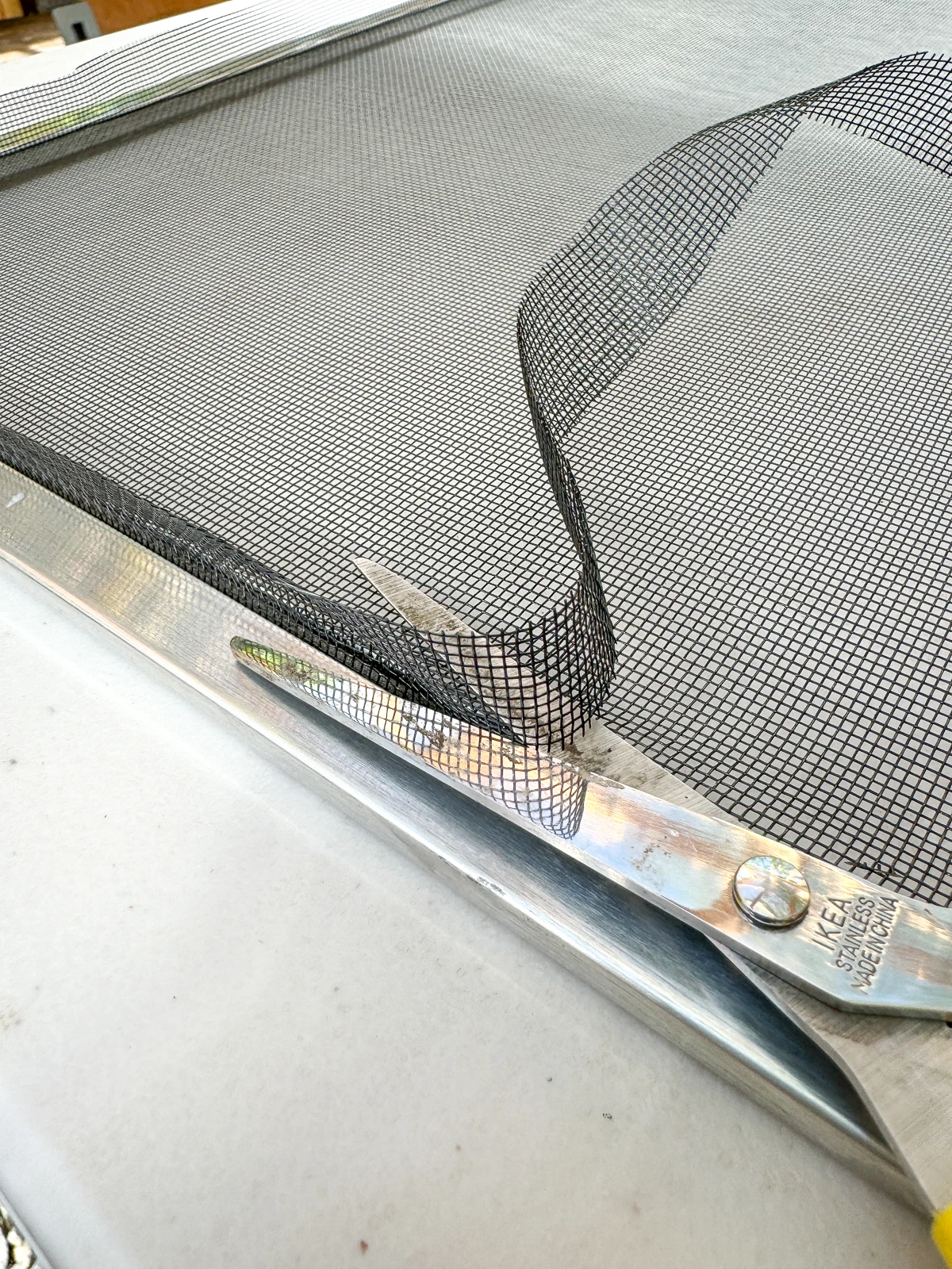 trimming the excess window screen mesh with scissors