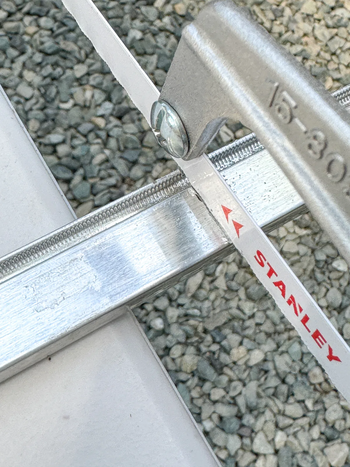 cutting DIY window screen frame pieces with a handheld hacksaw