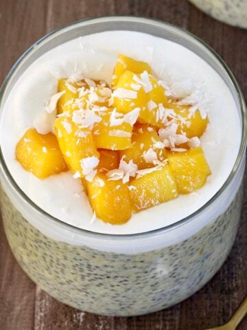 Mango Chia Pudding in a glass jar with a gold spoon nearby.