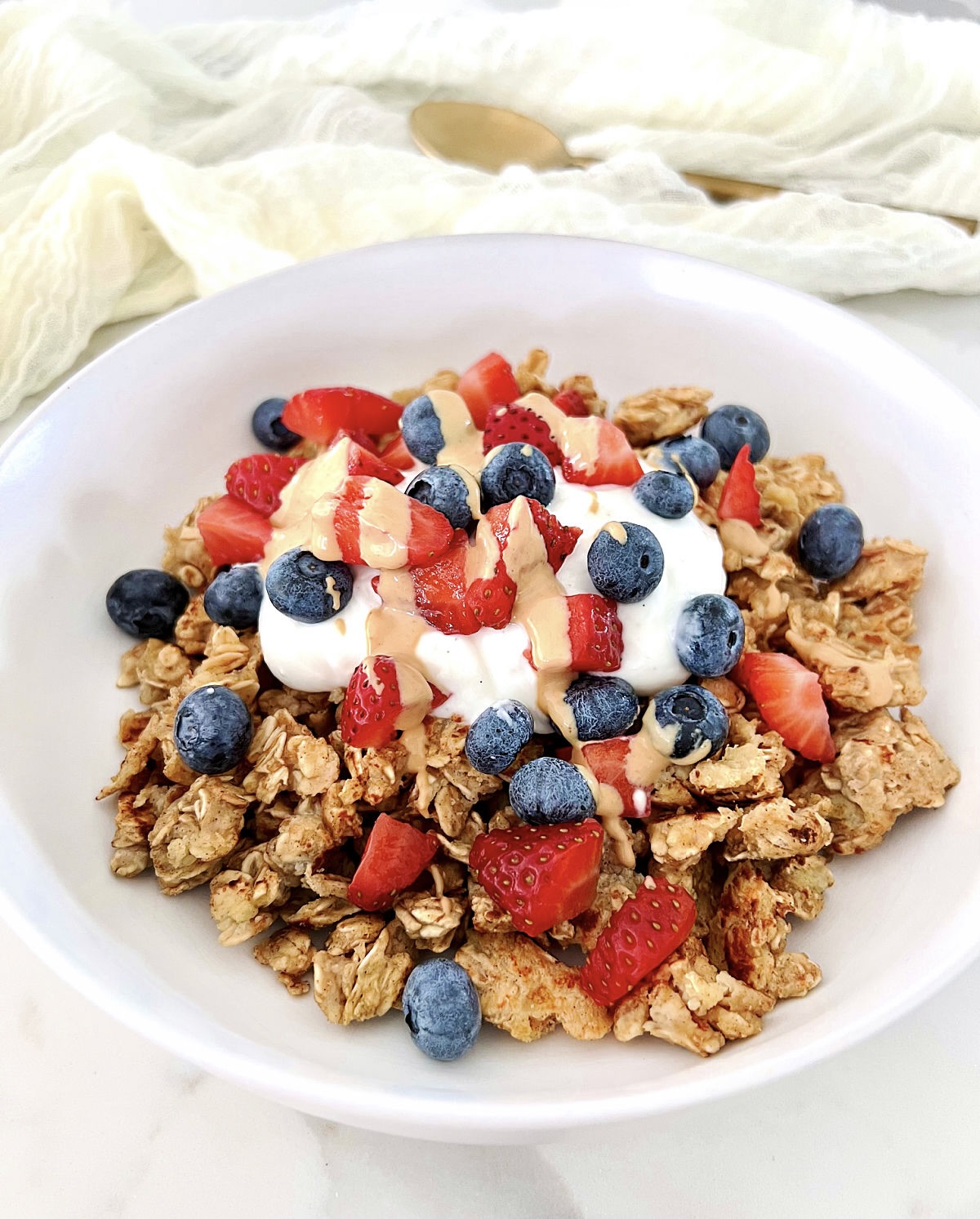 Scrambled oats in a white bowl topped with Greek yogurt and berries.