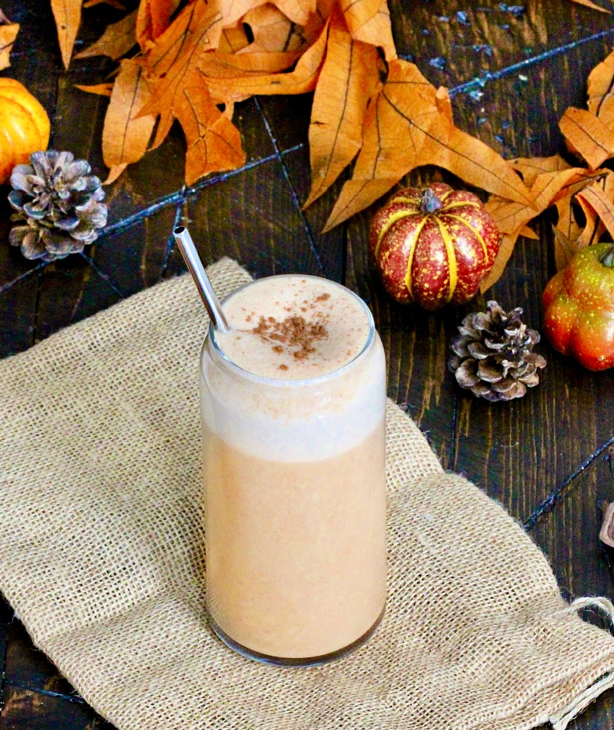 Pumpkin Spice Protein Shake surrounded by fall leaves and decorative pumpkins.