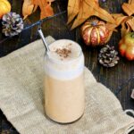 Pumpkin Spice Protein Shake surrounded by fall leaves and decorative pumpkins.