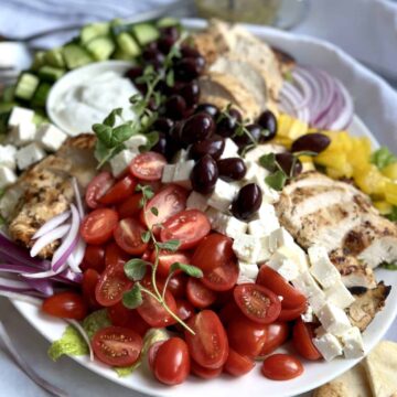 Grilled chicken souvlaki salad on a white platter.
