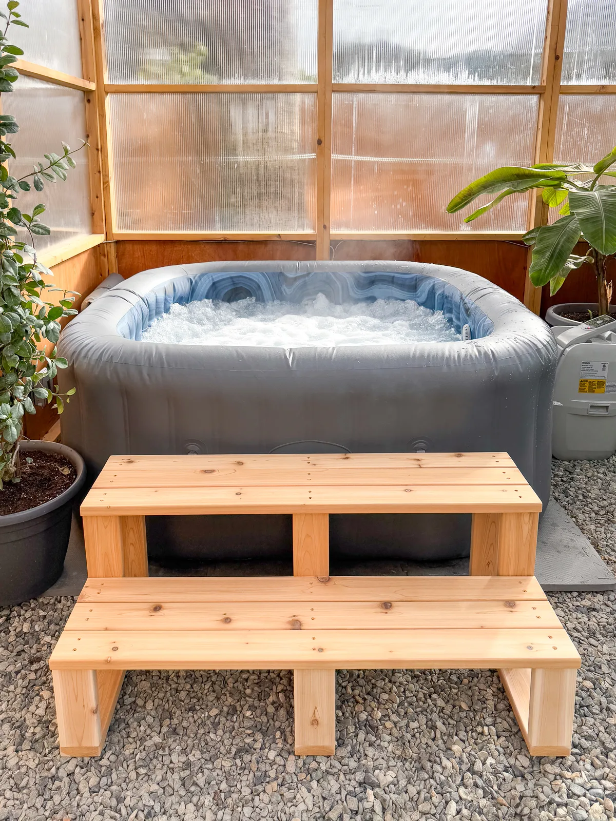 DIY hot tub steps in front of inflatable hot tub in greenhouse