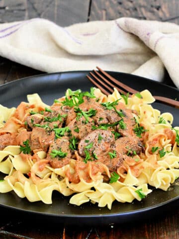 Mushroom Paprikash on a black plate on a wooden board.