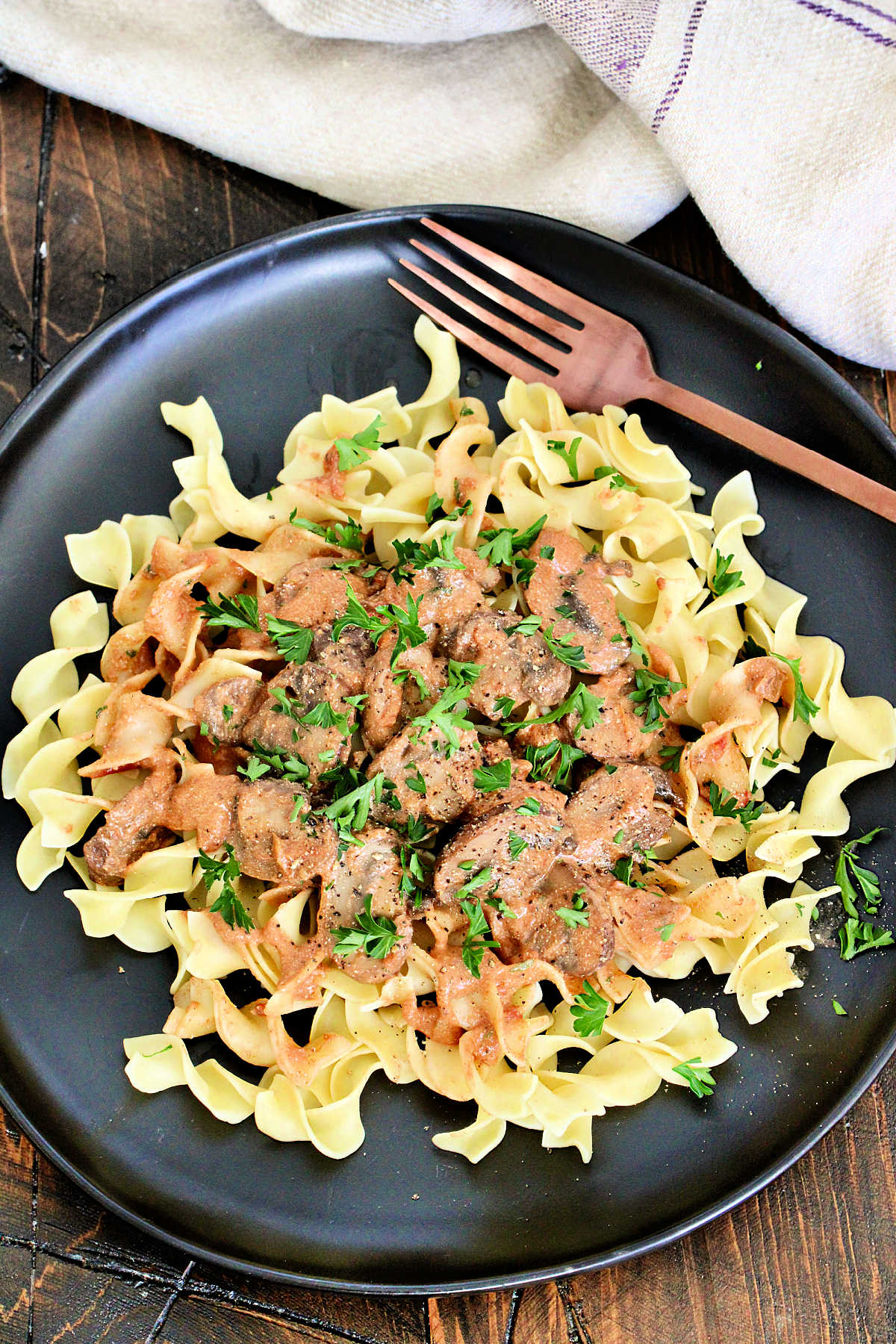 Mushroom Paprikash on a black plate on a wooden board.